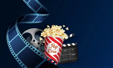 An unspooled reel of film curls around an overflowing popcorn tub and a film clapper.