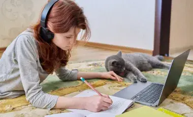 Girl studying on the floor with her cat. 