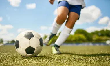 childs legs kicking a soccer ball