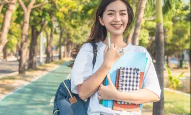 A young student walking along a path of a college campus.