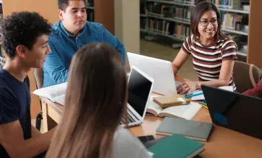 Five students sitting at a table, working with their laptops