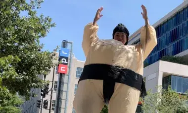 Person with upraised arms in inflatable sumo wrestler costume