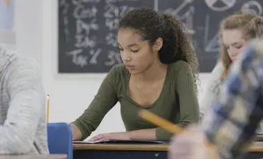 Teenage girl in a classroom working at her desk. 