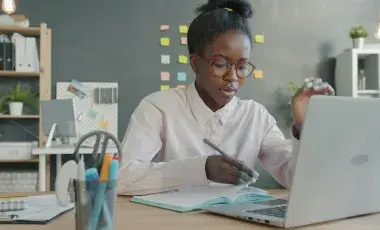 Woman infront writing in front of laptop