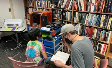 Two patrons in front of 3D printers