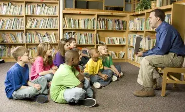 A man reads to a group of young students