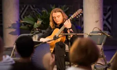Misha Cyrevian playing a classical acoustice guitar in front of an audience