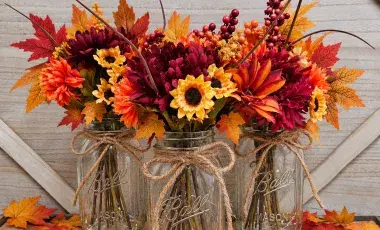 mason jars with fall colored artificial leaves and flowers