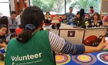 Volunteer reading to a group of kids and their caregivers.