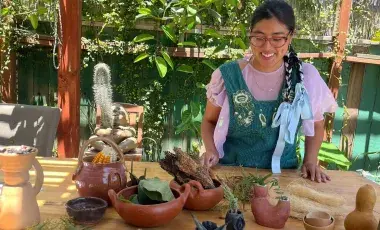 A woman wearing an apron in front of handmade clay objects. 