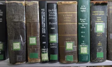 historic reference books on the subject of patents fill a book shelf