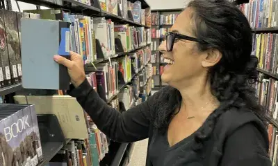 person pulls item from bookshelf