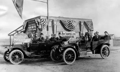 In foreground, groups of men sitting in two different cars, 1911.