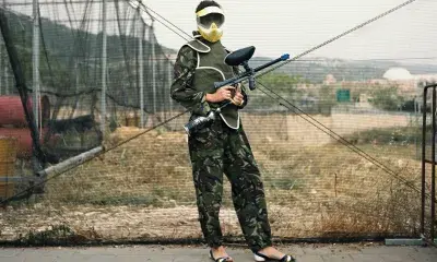 Soldier wearing fatigues and feminine sandals holds gun