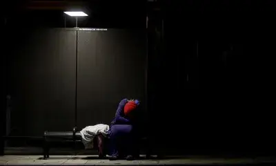 Person sleeping at bus stop at night, 2017