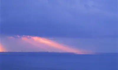 Seascape with blue hue of clouds and sunrays