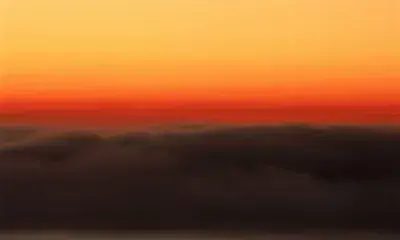 Sky during sunrise featuring a gradient of orange and dark clouds