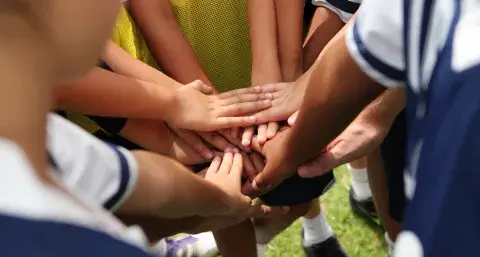 kids hands all together in a team circle