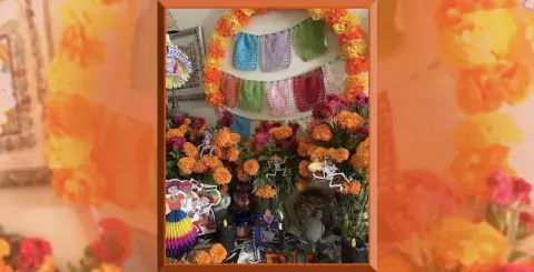 Altar con flores de cempasúchil, velas, y nicho