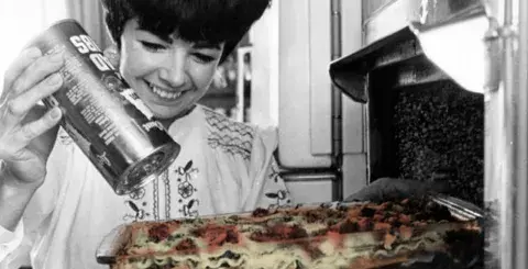 Women sprinkles cheese on lasagna