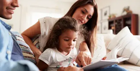 a Latinx family reads aloud together on the couch