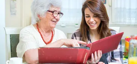 teen helping a senior look at a photo album