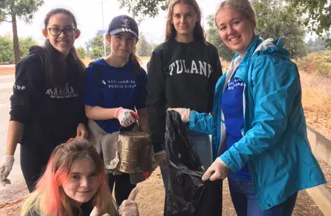 five teens cleaning up a park
