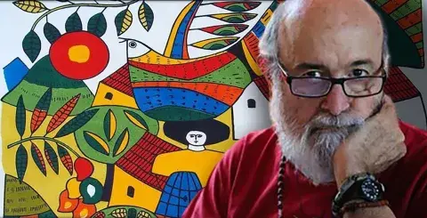 Fernando Llort with his art in the background.