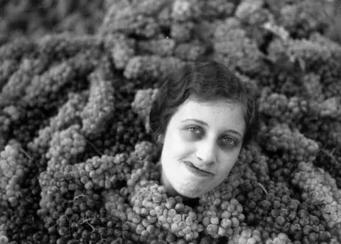 woman covered up to her neck in grapes