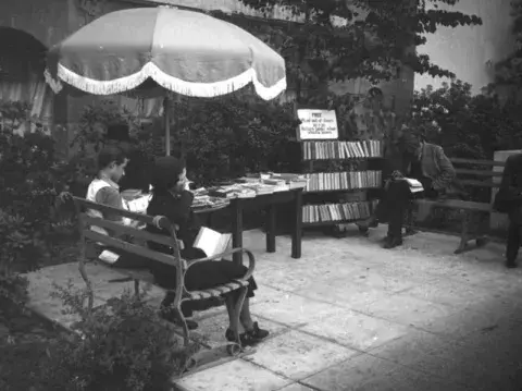 2 people reading under an umbrella, 1937