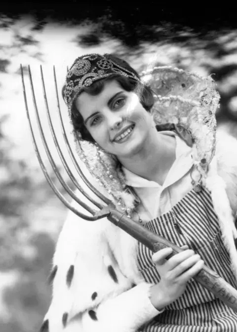 woman in a crown holding a giant fork