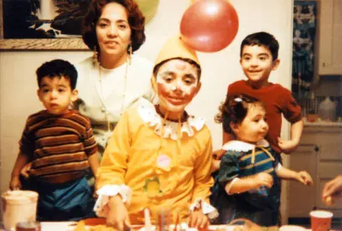 A mother with her children at a party. One child is dressed as a clown.