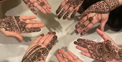 A group of hands in a circle with henna tattoos