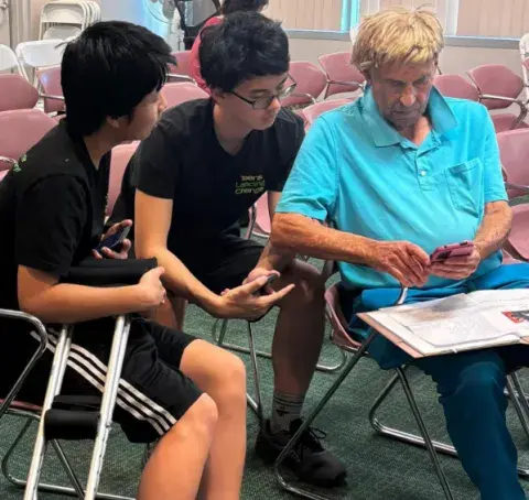 2 teens looking a a senior's phone