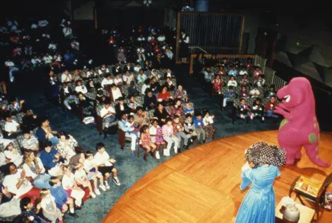 An audience of children and their families watch Barney the Dinosaur