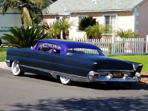 purple lowrider car by a white picket fence