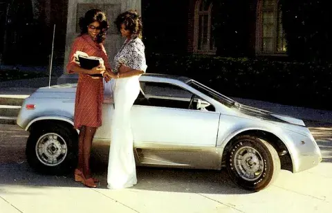 two woman stand in front of futuristic car