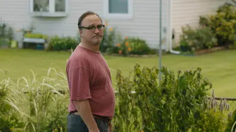 film still of Jim Belushi standing outside next to grass