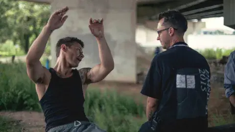 two men talking under a bridge