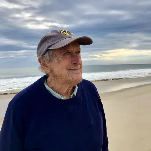 André Gregory in a cap and sweater at the beach