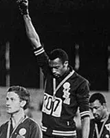 Tommie Smith and John Carlos raising their fists with bowed heads while receiving the gold and bronze medals
