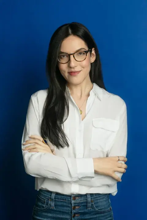 Sloane Crosley with her arms crossed against a bright blue wall