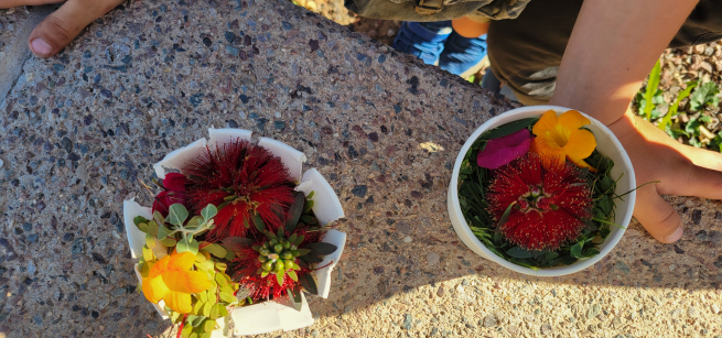 hand next to a bird's nest made with a soup cup and flowers