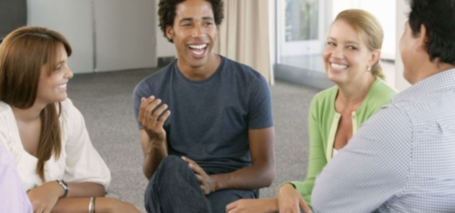 A class of four people in a conversation circle, smiling and having a wonderful time.