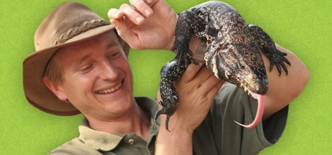 Man in hat holding large lizard