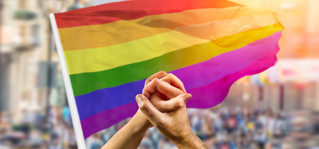 hand-holding in front of a rainbow flag