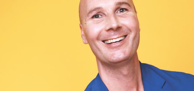 Christopher T. Magician facing the camera and smiling. Wearing a blue blazer.