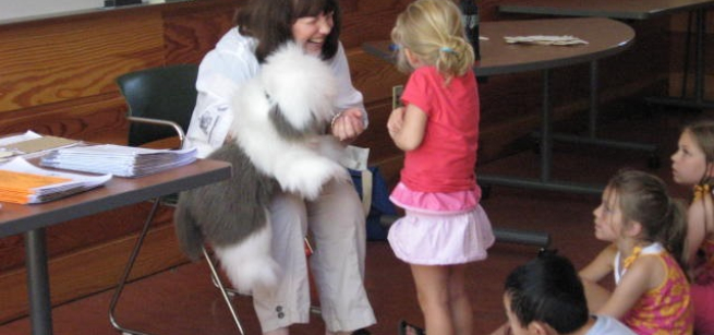 The performer holding a stuffed dog and talking with a patron.