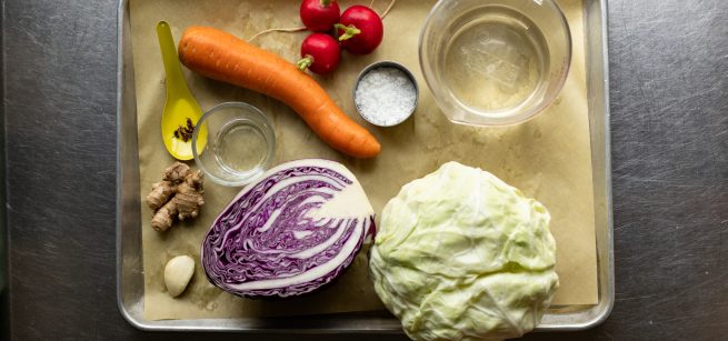 a tray holds a variety of vegetables and supplies for pickling