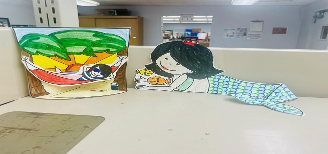 A paper craft of a child in a hammock and a mermaid 